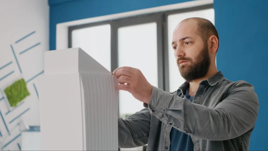 Man inspecting a pleated HVAC air filter before replacing it at home.