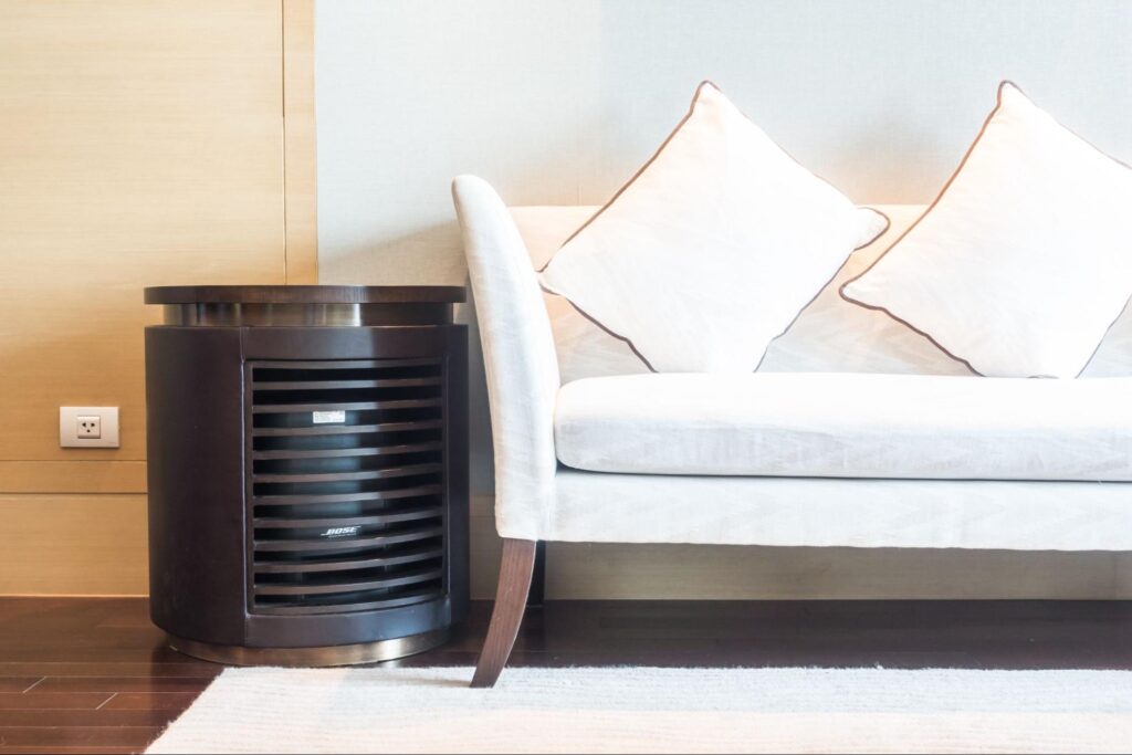 Indoor air vent unit placed beside a modern white sofa, showing typical home ventilation equipment in a living room setting.