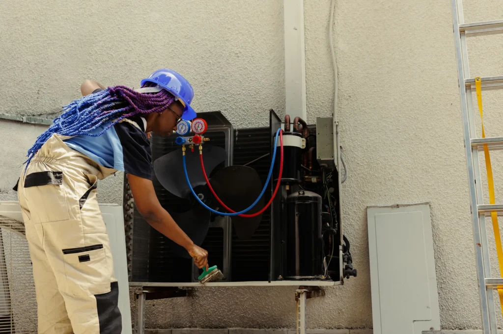 HVAC technician cleaning AC condenser coils during routine HVAC maintenance service