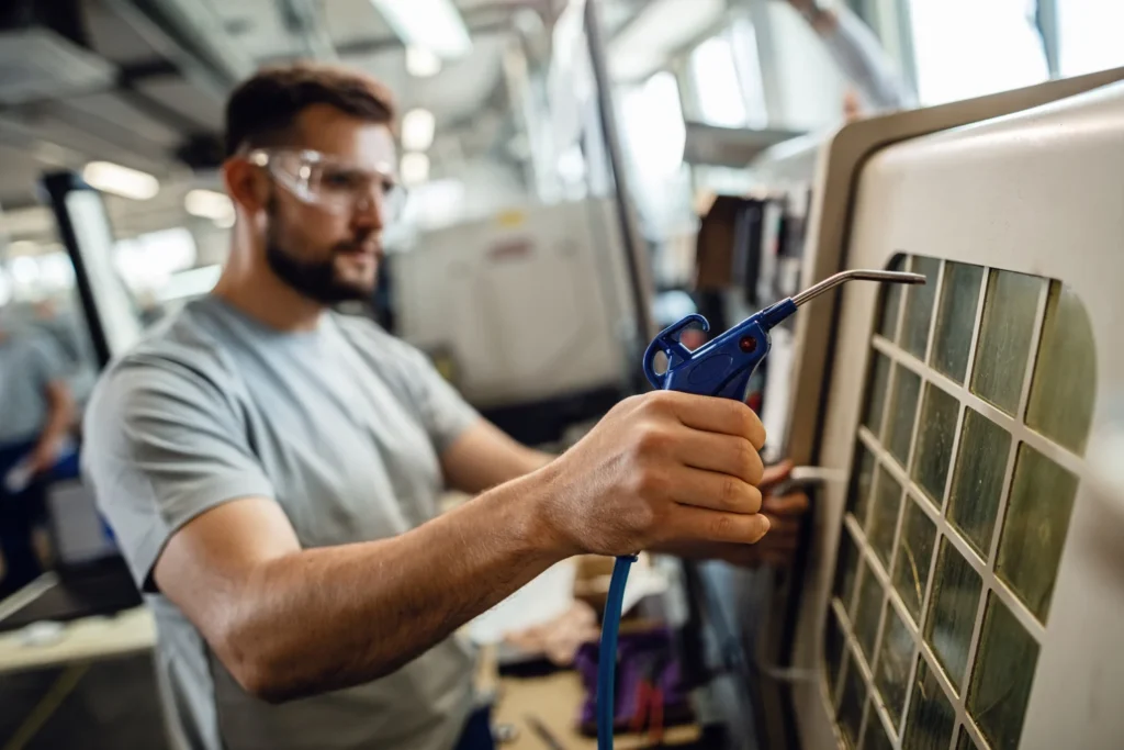 HVAC technician cleaning air filter using compressed air during maintenance service